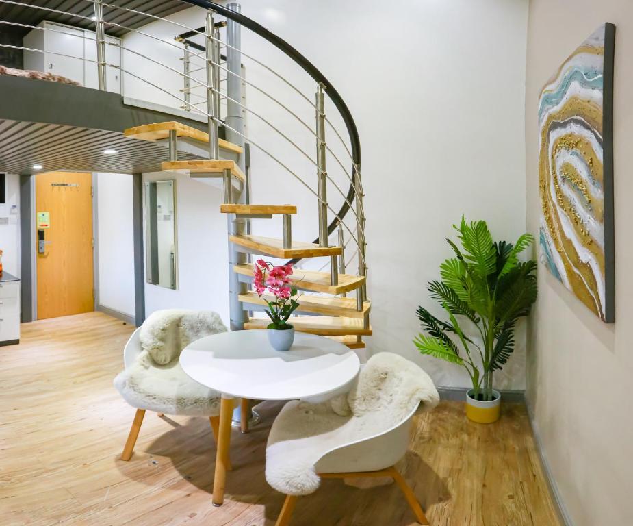a room with a table and chairs and a spiral staircase at E101 Urban chic loft in Coventry