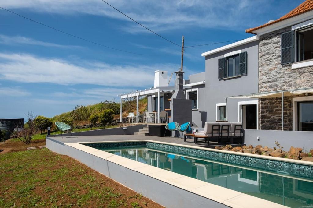 a villa with a swimming pool in front of a house at GuestReady - Quiet house & heated pool w sea view in Prazeres