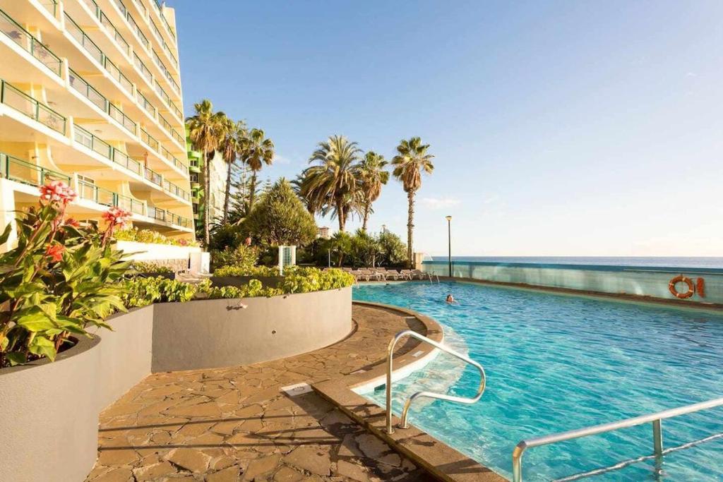 a swimming pool next to a building and the ocean at Formosa Sunset - Em frente à praia com wifi in Funchal