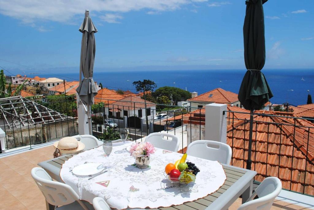 una mesa en un balcón con vistas al océano en Vila Rosa - Renovated House Overlooking The Sea, en Funchal