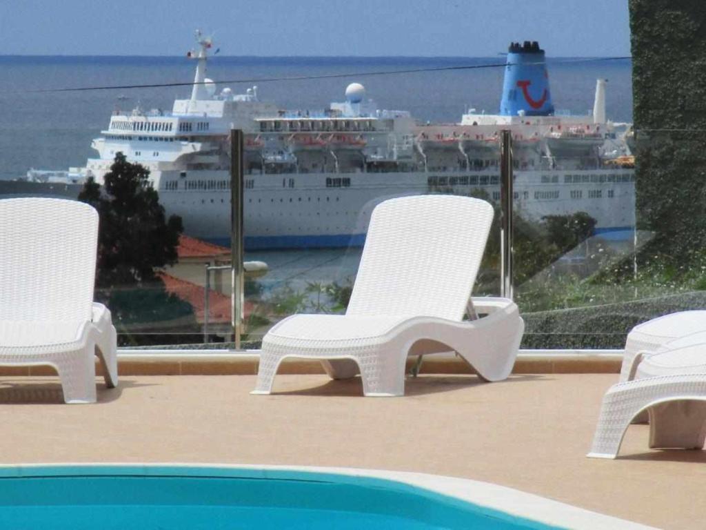 three chairs and a cruise ship in the water at GuestReady - Nora Premium in Santa Luzia