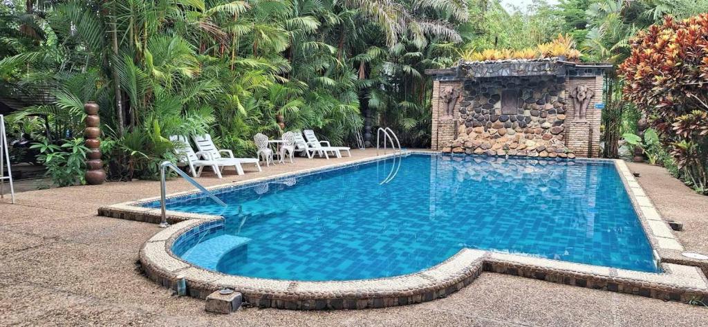 a swimming pool in a resort with chairs and trees at Hotel Khaosok and Spa in Khao Sok National Park