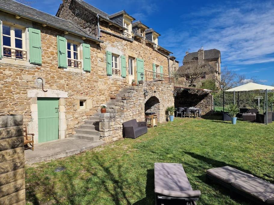 un edificio de ladrillo con una puerta verde y un patio en Gîte de Montrozier, en Montrozier