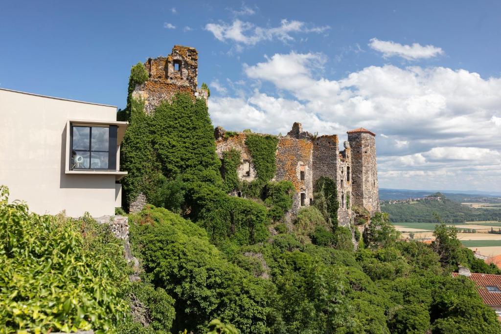 un castillo en la cima de una colina con árboles en Hôtel & Restaurant Origines par Adrien Descouls - Teritoria en Issoire