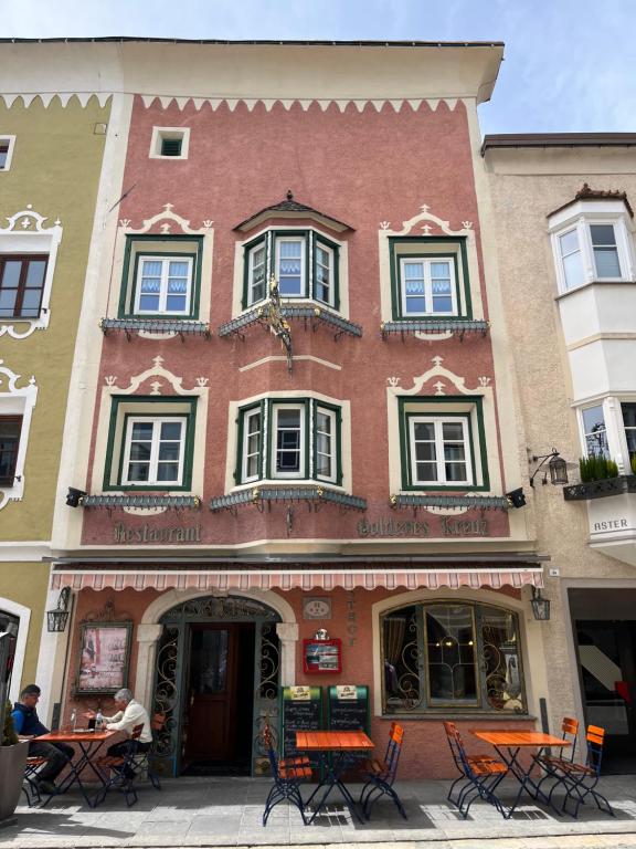 un bâtiment avec des tables et des chaises devant lui dans l'établissement goldenes kreuz, à Vipiteno