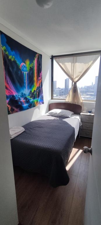 a bedroom with a bed with a painting on the wall at Departamento Parque O'Higgins in Santiago