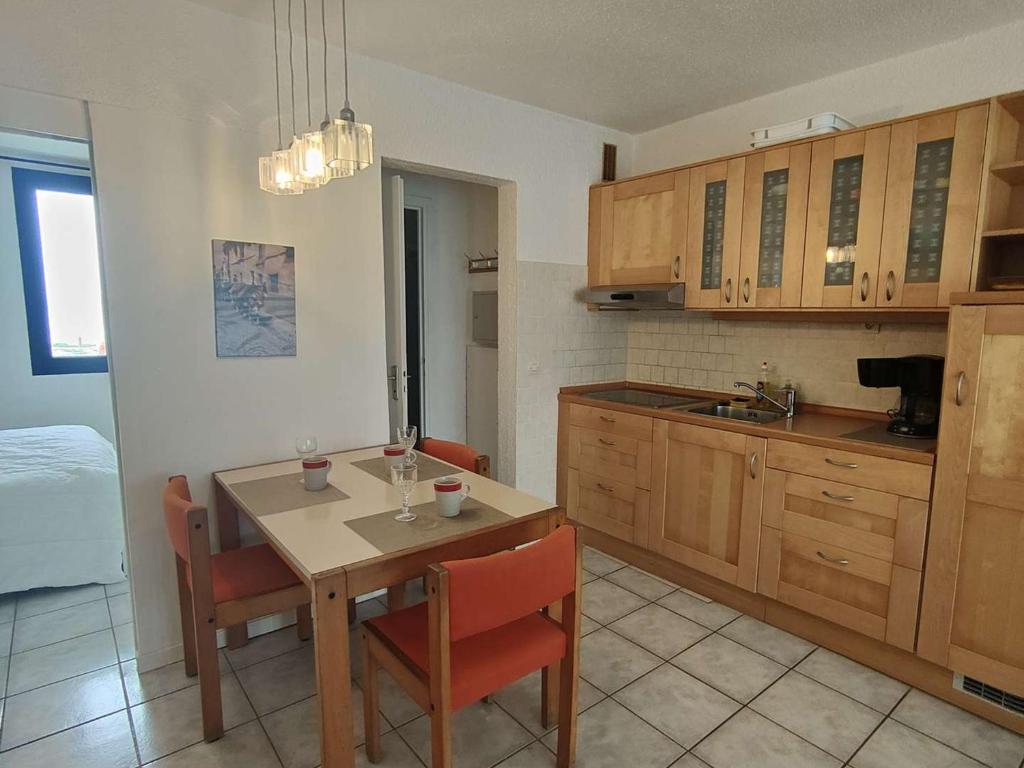 une cuisine avec une table et des chaises dans une pièce dans l'établissement Appartement T2 avec Terrasse et Piscine, Parking Privé, Espace Aquatique - Le Barcarès - FR-1-195-22, au Barcarès