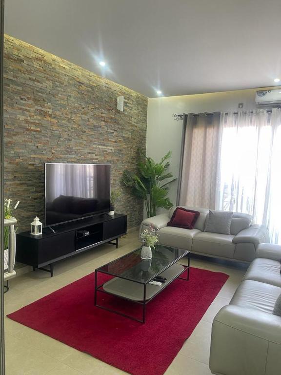 ein Wohnzimmer mit einem Sofa und einem Flachbild-TV in der Unterkunft Évasion saisonnière sacré cœur in Dakar