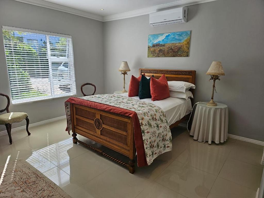 1 dormitorio con 1 cama grande con almohadas rojas en Chocolate Box Guesthouse, en Gordonʼs Bay