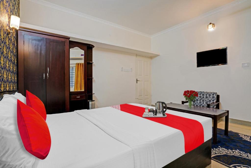 una camera d'albergo con letto e cuscini rossi di Flagship South Fort Inn a Alleppey
