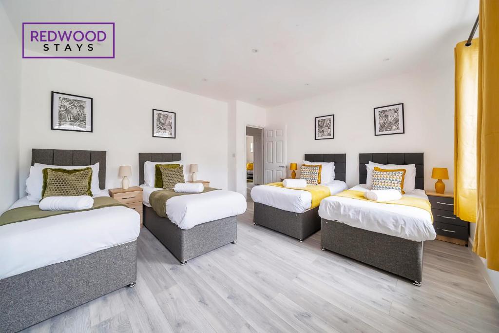 a room with four beds and a sign that reads redwood stays at Well-Equipped Serviced Apartments in Aldershot Town Centre, Free WiFi By Redwood Stays in Aldershot