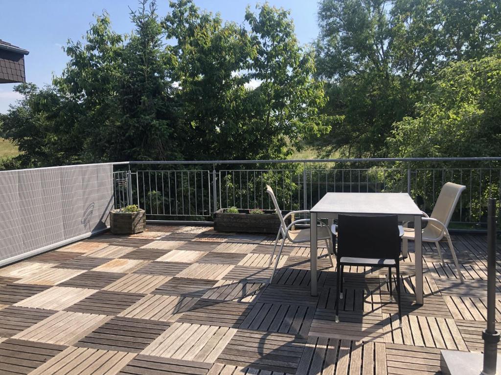 eine Terrasse mit Tisch und Stühlen auf einem Deck in der Unterkunft Ferienwohnung Blick ins Grüne in Ober-Ramstadt