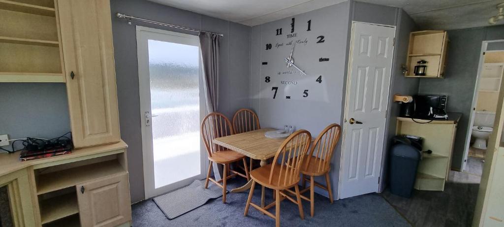 a kitchen with a table and chairs and a clock on the wall at Seaside View Holiday Home in Aberystwyth