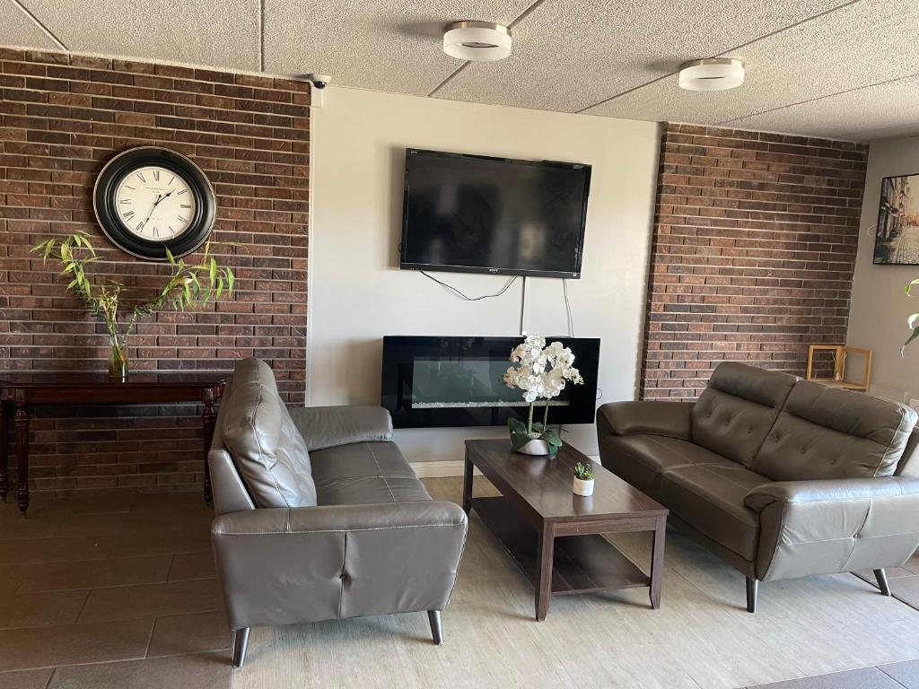 a living room with two couches and a clock on a brick wall at Motel St-Eustache in Saint-Eustache