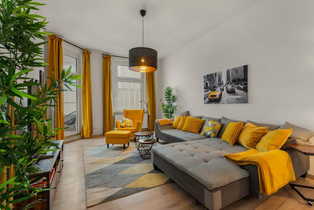 LoC - Oldenburg Altstadtlage في أولدنبورغ: غرفة معيشة مع أريكة رمادية ووسائد صفراء