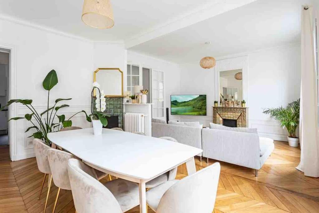 un salon avec une table et des chaises blanches dans l'établissement Grand appartement familial, à Paris