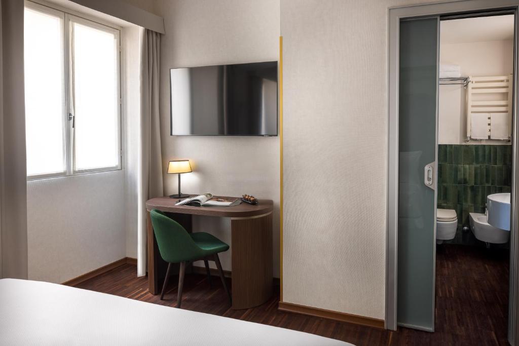 a hotel room with a desk and a bathroom at Maison Roma Piazza di Spagna UNA Esperienze in Rome