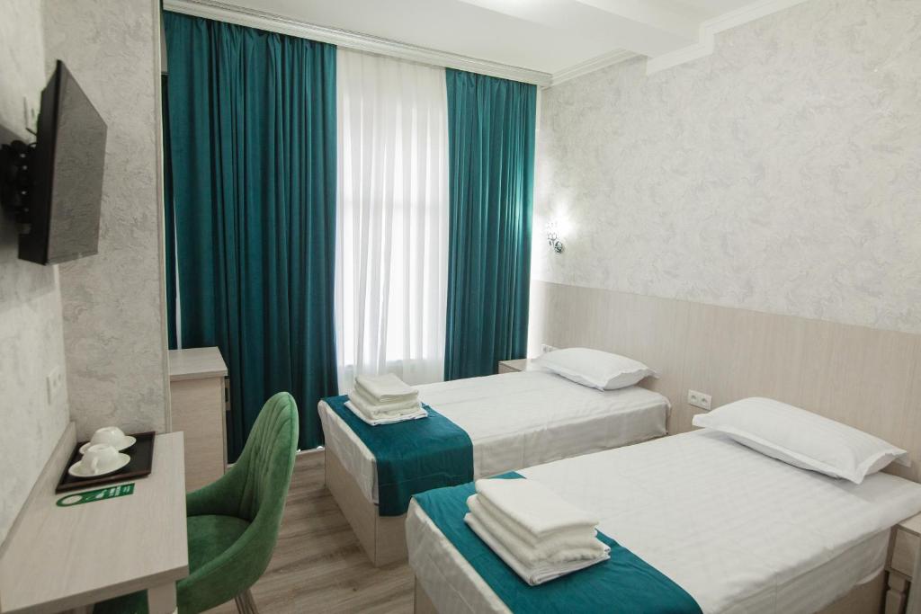 ブハラにあるHOTEL MERCURI-MERIDIANのベッド2台とテレビが備わるホテルルームです。