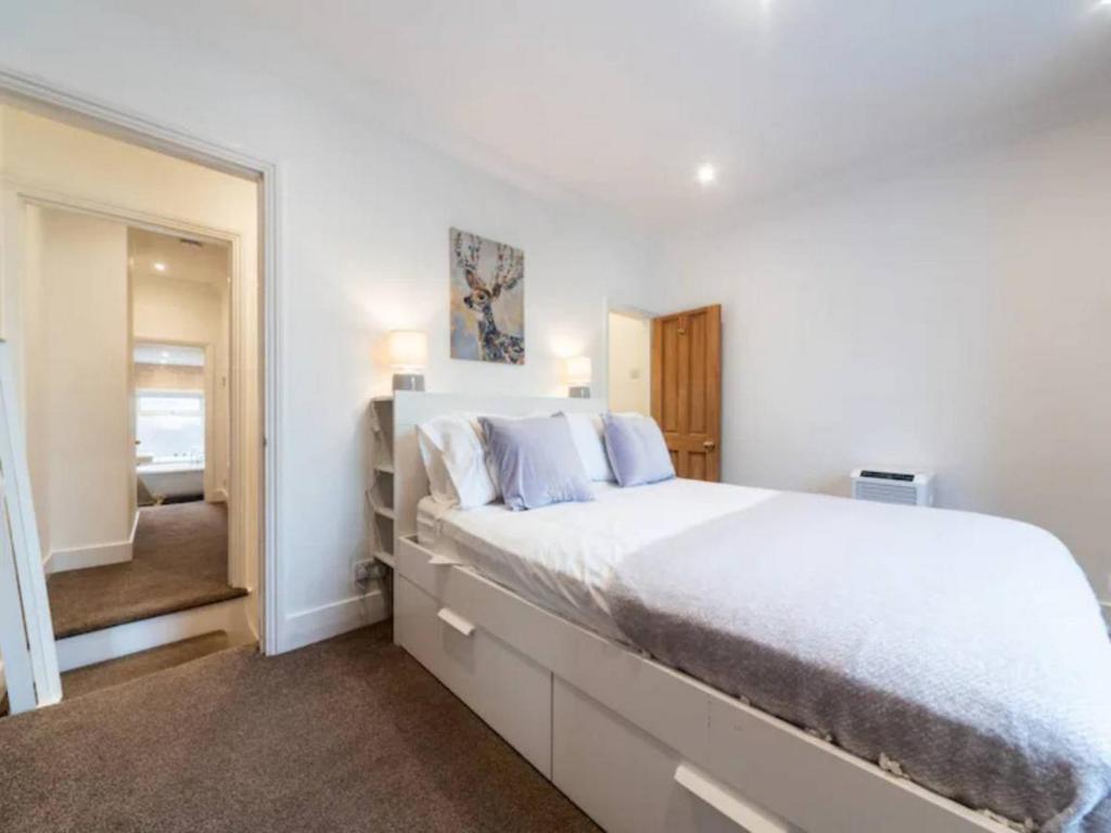a white bedroom with a large bed and a mirror at Charming Period Home near Surbiton with Garden in London