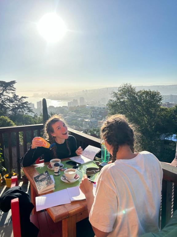 Dos mujeres sentadas en una mesa en un balcón en Meraki Hostel - Cerro Alegre - Valparaíso, en Valparaíso