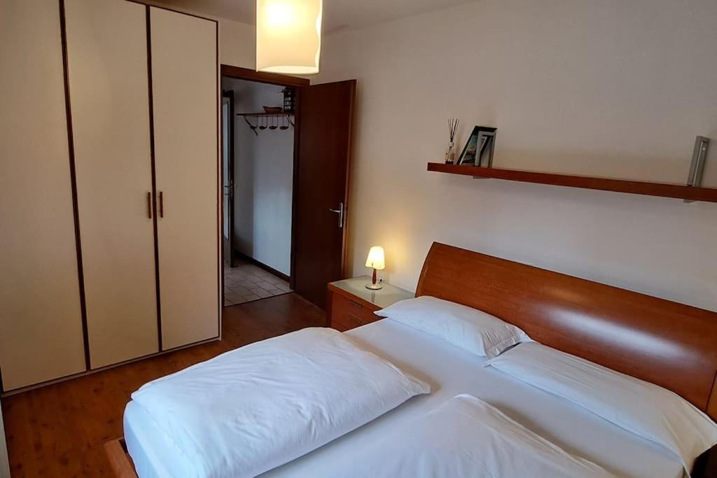 a bedroom with a white bed with a wooden headboard at Little apartment in Dolomiti in Vigo di Cadore