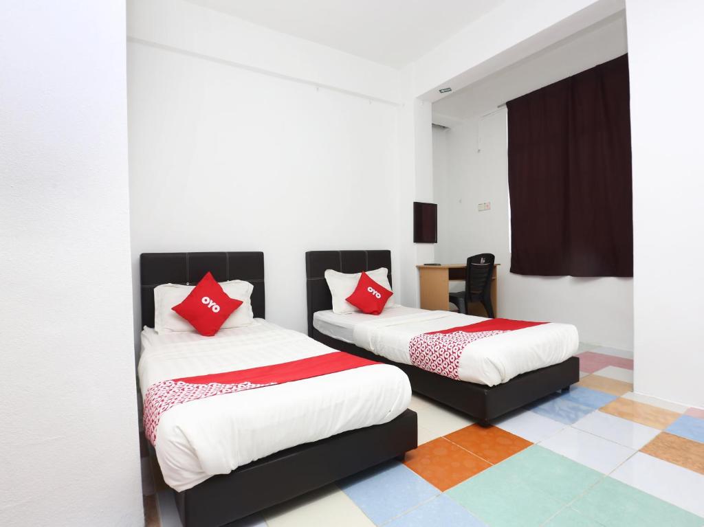 2 bedden met rode kussens in een kamer bij KB Rest Inn-Twin Single in Kota Bharu