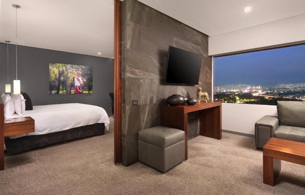 A bedroom-and-sitting area with a television wall and illuminated night view.