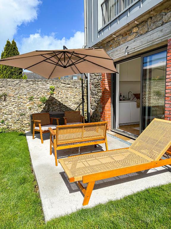 un groupe de bancs avec un parasol sur une terrasse dans l'établissement L’Abri-Cotier - Maison rénovée, à Dinard
