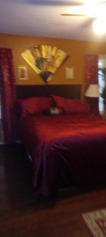 um quarto com uma cama com um edredão vermelho em Vanessa rooms em Harker Heights