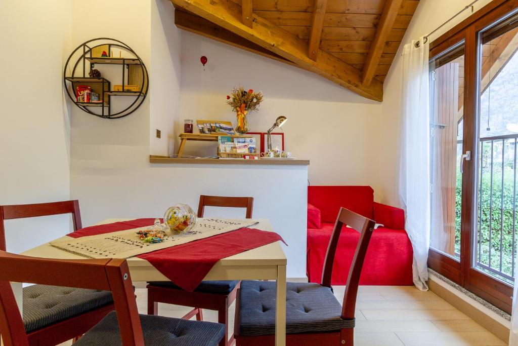 una sala da pranzo con tavolo, sedie e divano rosso di CasaCri a Cittiglio