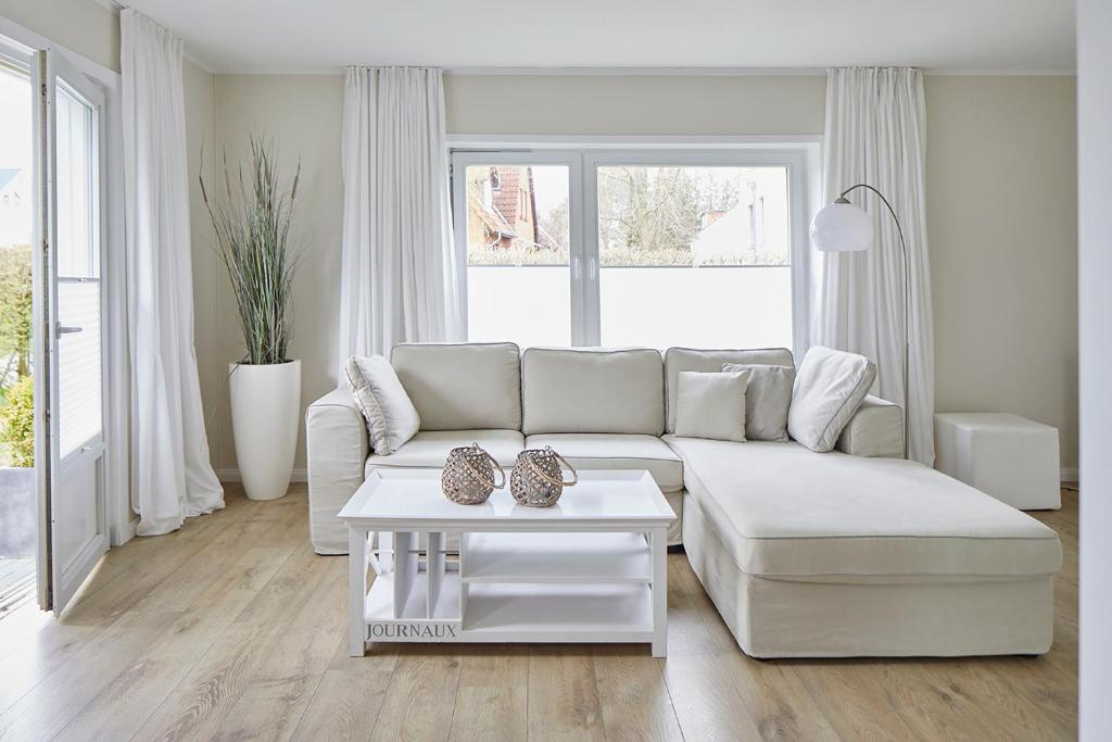 a white living room with a white couch and a table at Techts Sommerhaus in Timmendorfer Strand