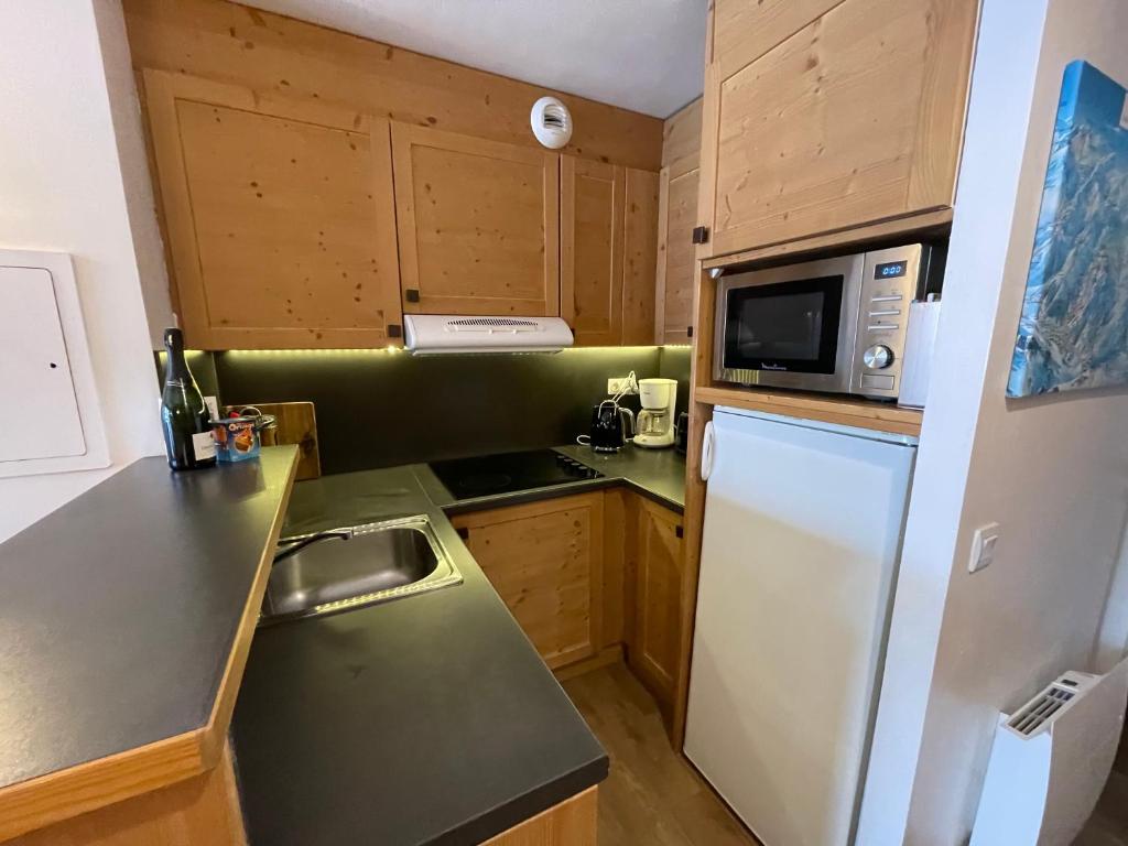 a small kitchen with a refrigerator and a microwave at Les Balcons de Bellevarde in Val-d'Isère