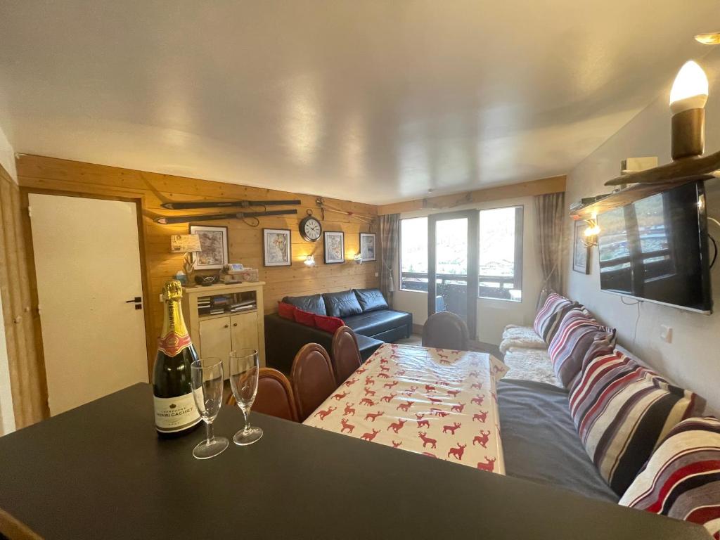 a living room with a couch and a table with a bottle of wine at Les Balcons de Bellevarde in Val-d'Isère