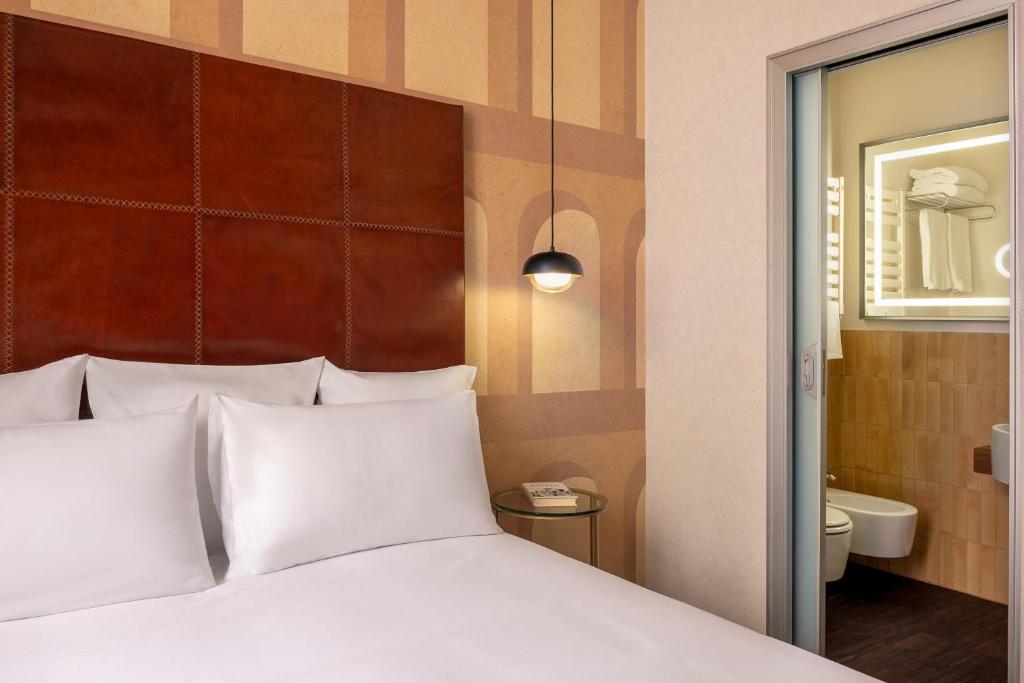 a bed with white pillows in a hotel room at Maison Roma Piazza di Spagna UNA Esperienze in Rome