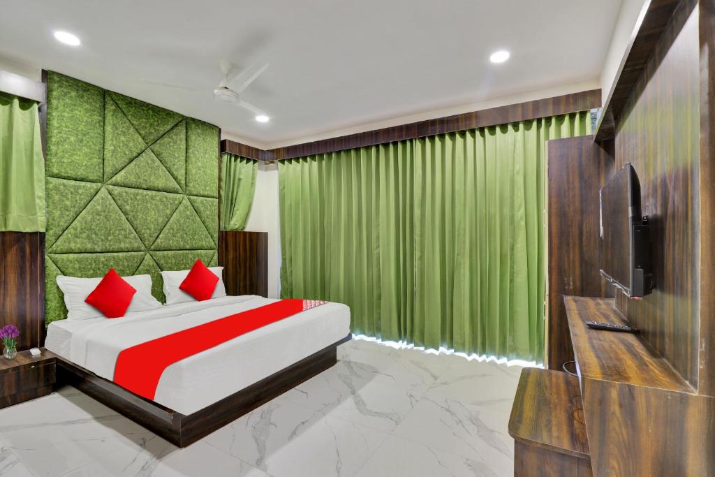 sypialnia z łóżkiem z zielonymi zasłonami i telewizorem w obiekcie OYO Hotel Stay Inn w mieście Bodakdev