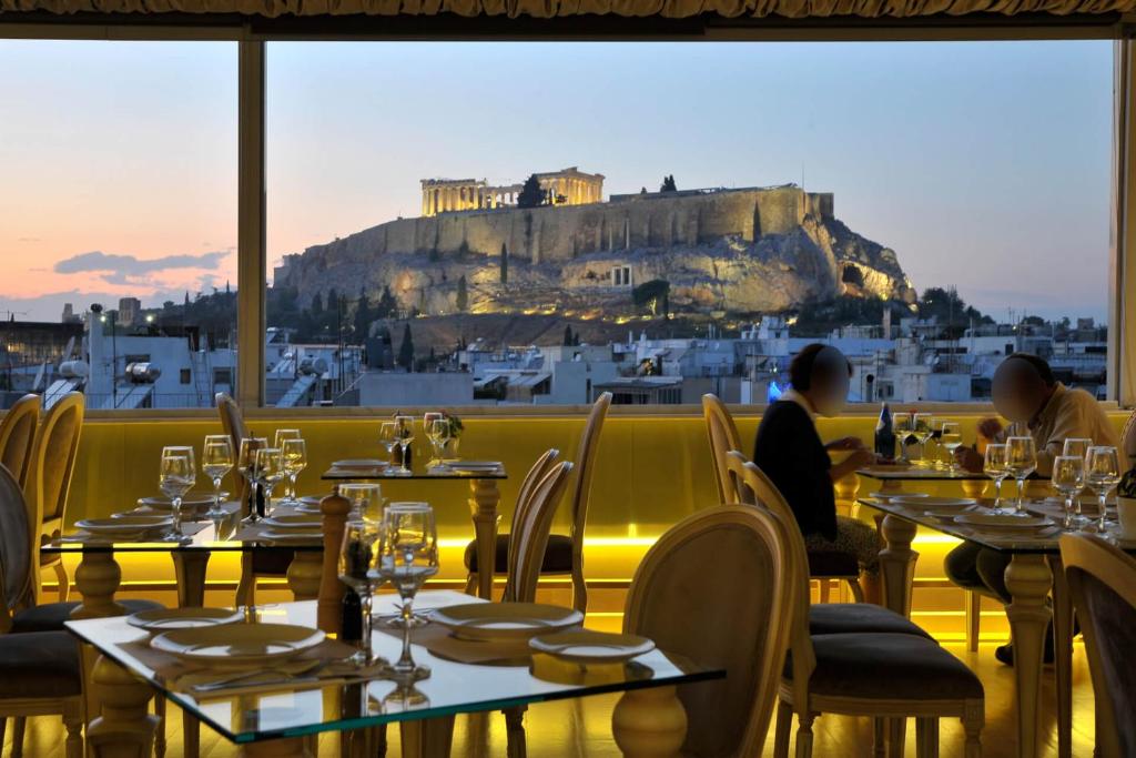a restaurant with tables and a view of the acropolis at Acropolian Spirit Boutique Hotel in Athens