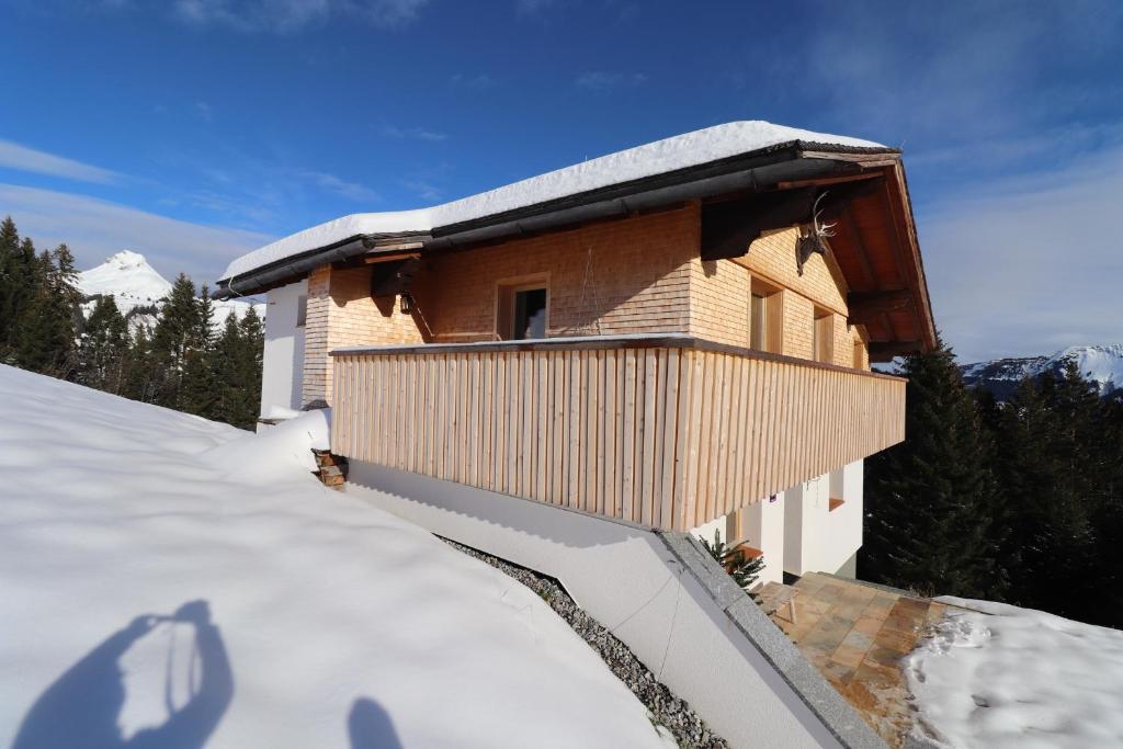 ein Haus mit schneebedecktem Dach auf einem schneebedeckten Hang in der Unterkunft Haus Haemmerle mit Ski in - Ski out in Damüls
