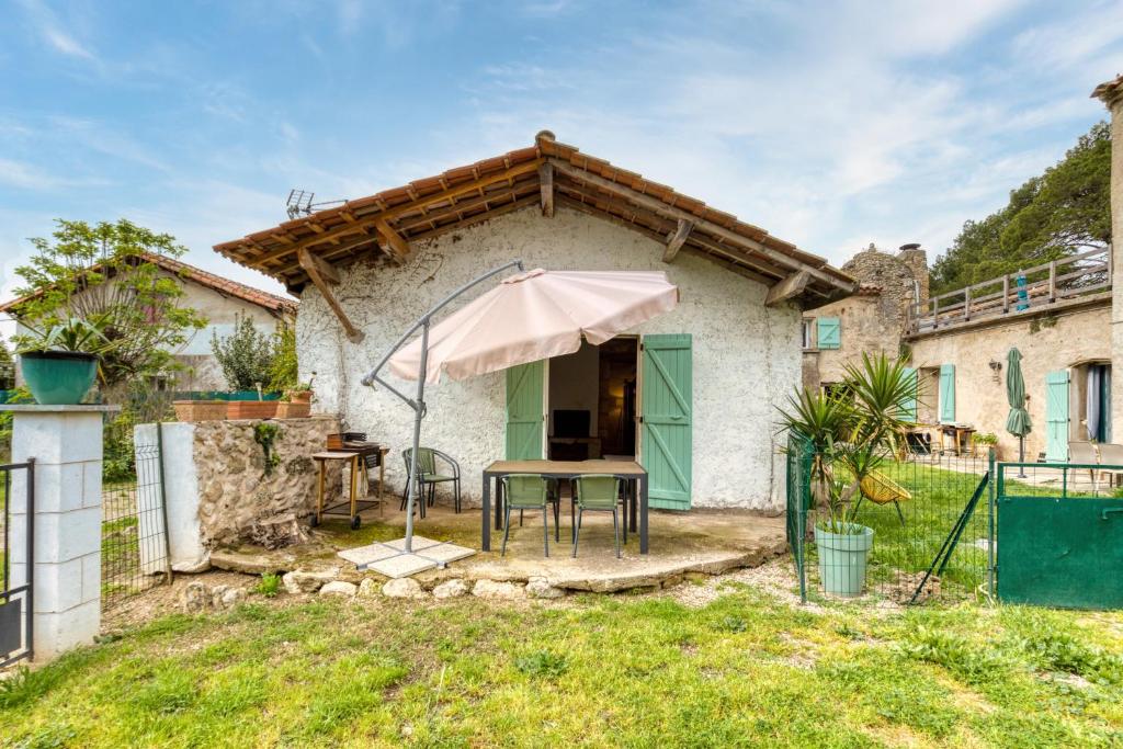 a table with an umbrella in front of a house at Maison de Campagne in Gignac