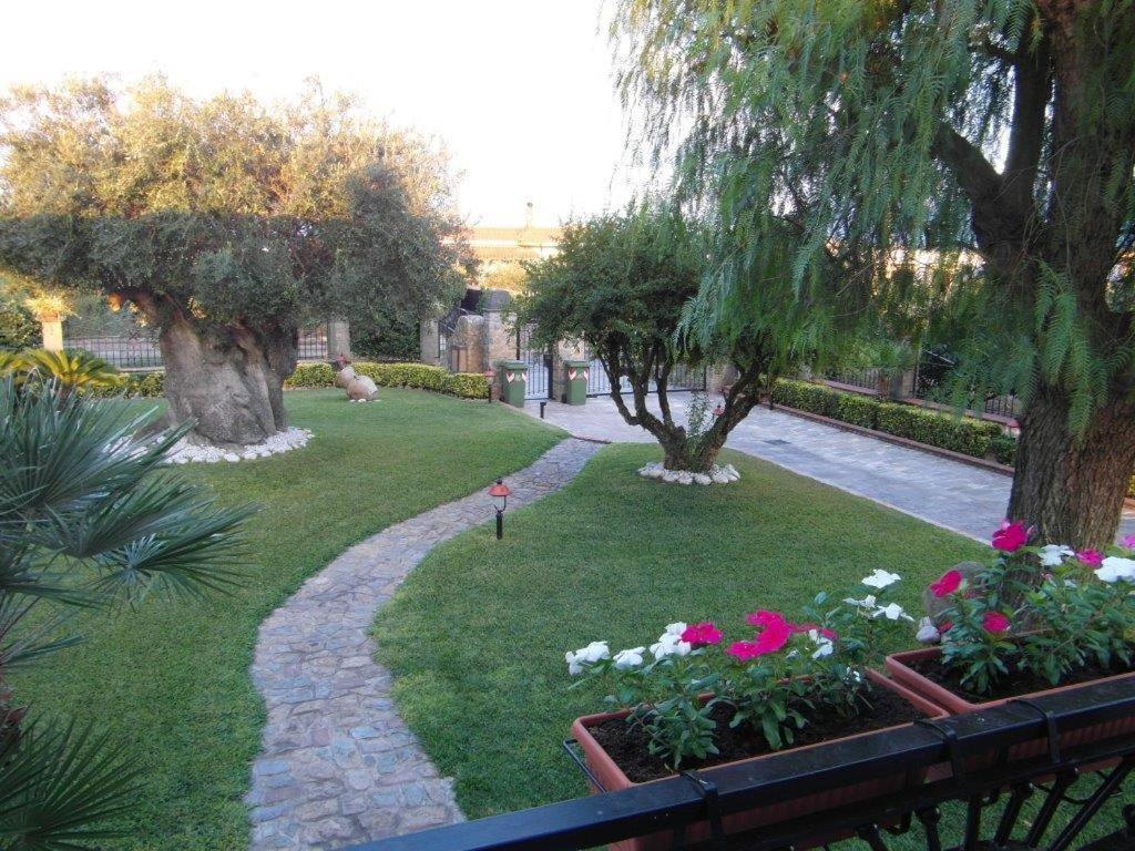un jardín con flores y árboles y una pasarela en B&B Villa Lura Pompei, en Pompeya