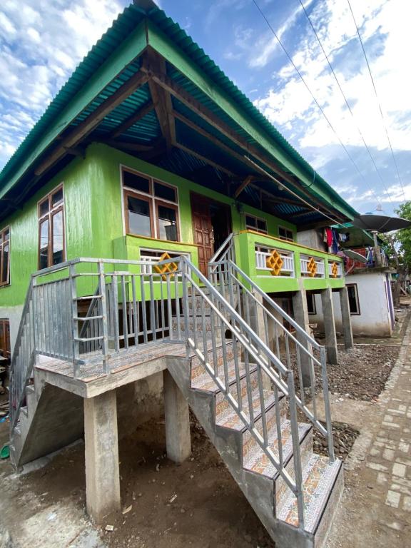 une maison verte avec un escalier en face de celle-ci dans l'établissement Dua Putri Komodo Homestay, à Komodo