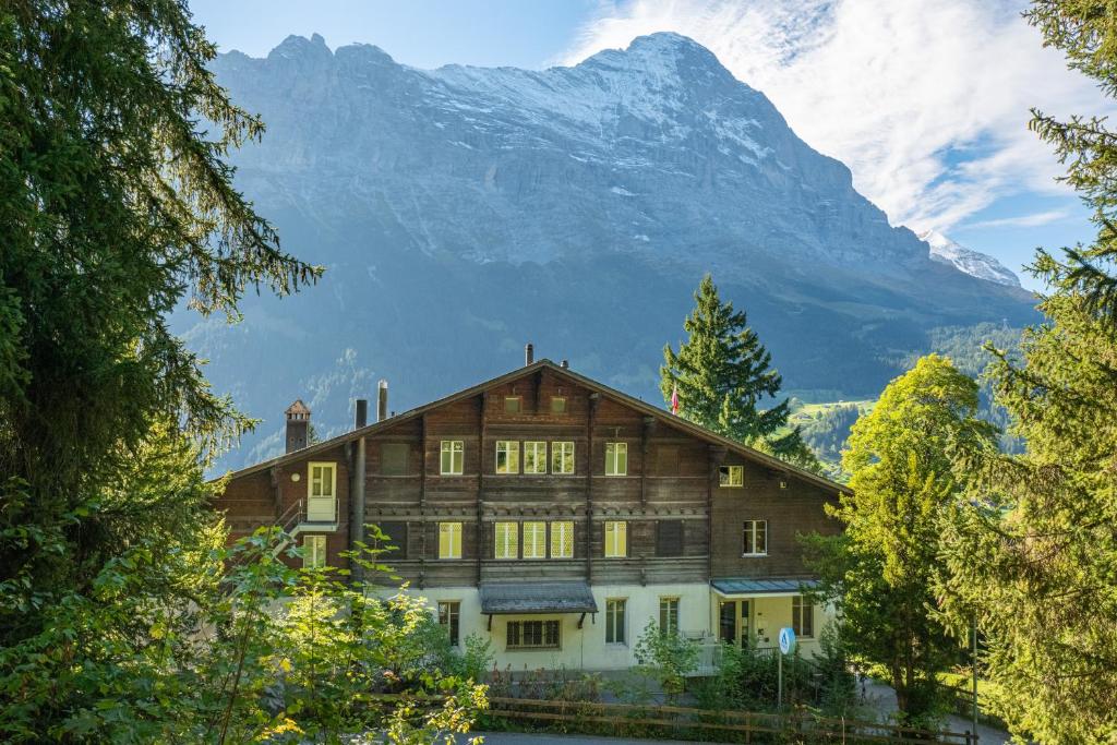 ein Haus mit einem Berg im Hintergrund in der Unterkunft Grindelwald Youth Hostel in Grindelwald