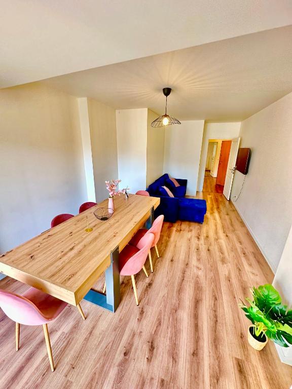 ein Esszimmer mit einem Holztisch und rosa Stühlen in der Unterkunft Elegant apartment Paris Bagnolet 303 in Bagnolet