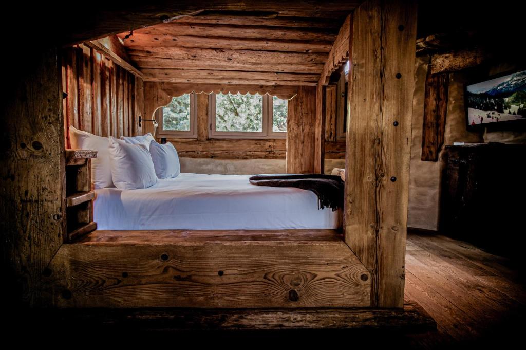 a bed in a wooden room with a window at Zannier Hotels Le Chalet in Megève