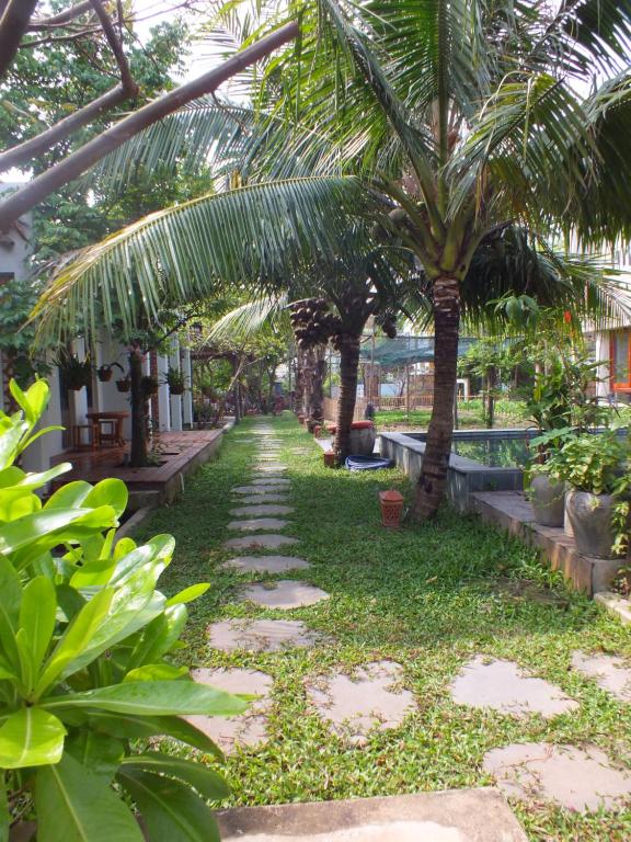 un jardin avec des palmiers et un sentier dans l'établissement Home Farm Villa Hoi An, à Hội An