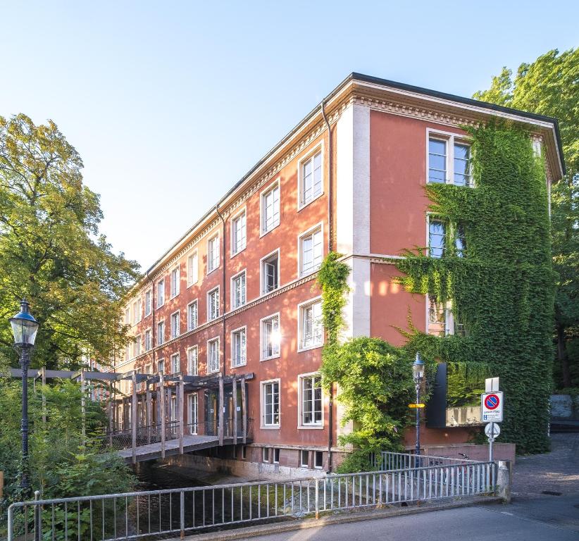 een rood bakstenen gebouw met een brug over een straat bij Basel Youth Hostel in Bazel