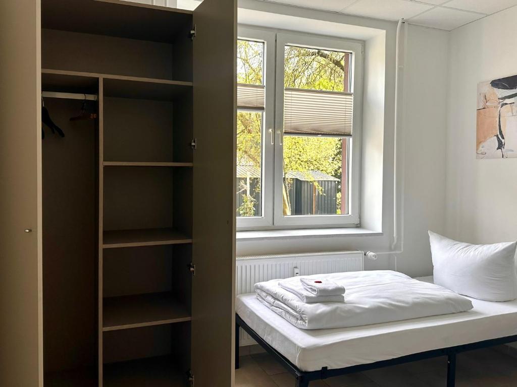 a small bedroom with a bed and a window at Craftsmen´s Comfort - Apartment by Comfort Housing in Falkensee