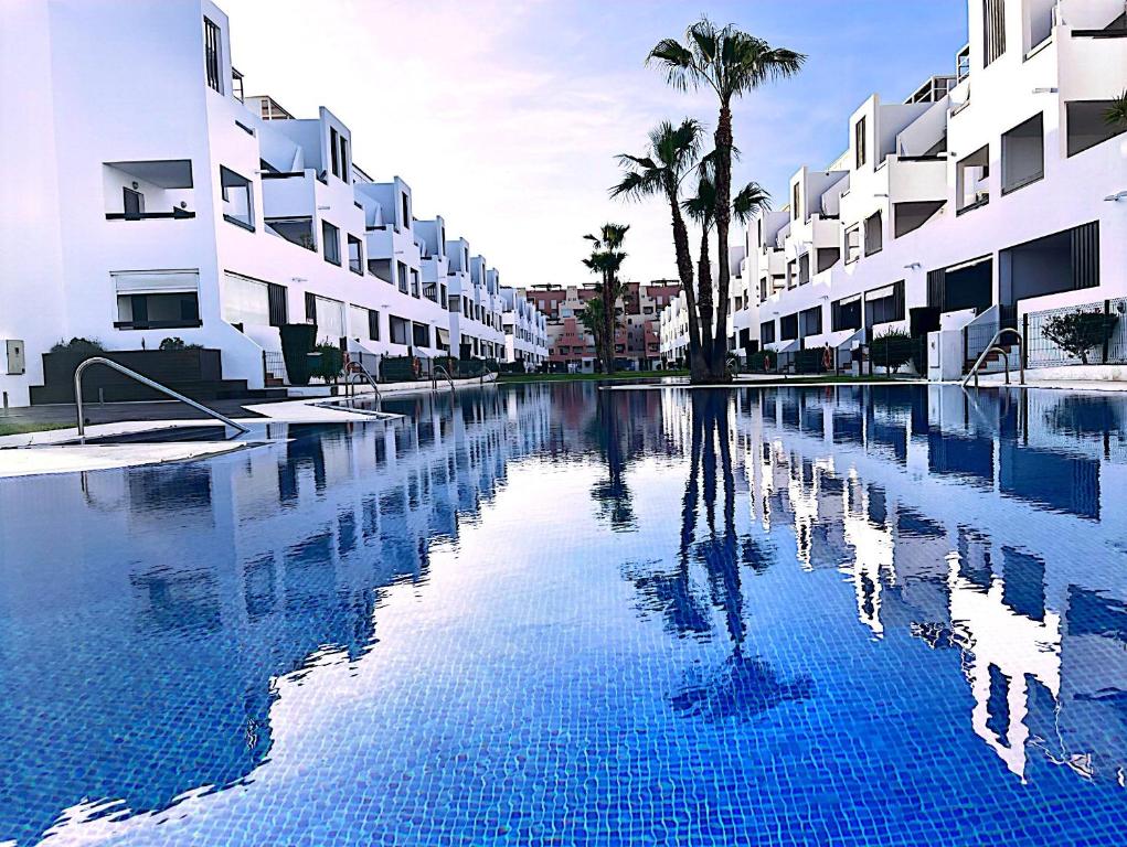 una gran piscina con palmeras y edificios en La Luz de Alborada, en Playas de Vera