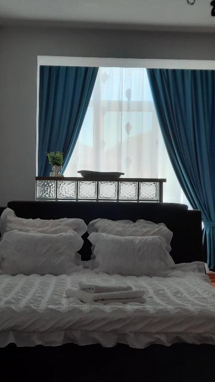 um quarto com uma cama com cortinas azuis e uma janela em Apartament Centru em Cugir