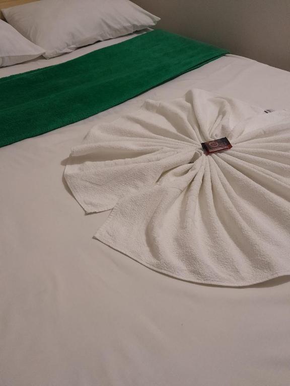 Una cama blanca con un vestido encima. en Hotel e Pousada Mape Ltda, en Guanambi