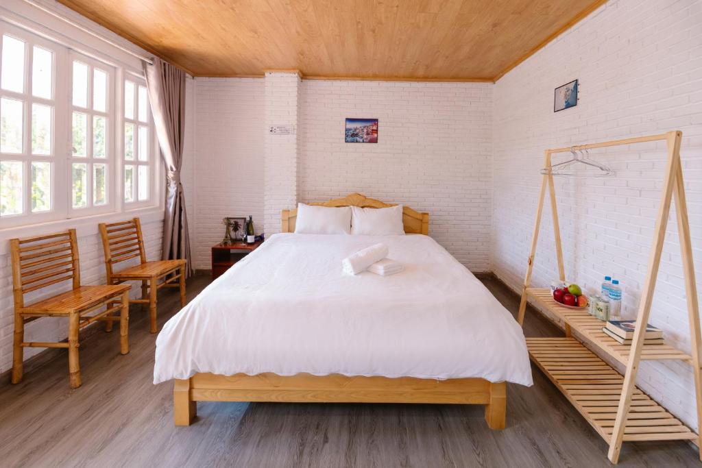 ein Schlafzimmer mit einem großen Bett und einem Stuhl in der Unterkunft Scent Room - Village in Da Lat